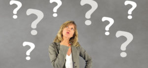 Woman wondering with questions marks and gray background