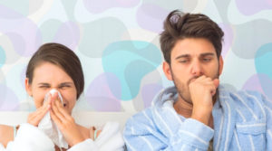 Woman sneezing, man coughing in printed background