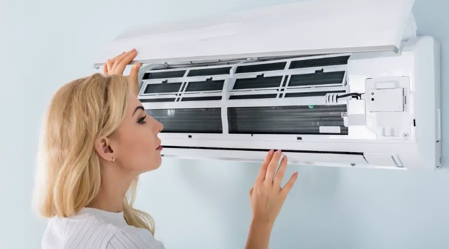 Woman with short, blond hair looking at the aircon filter